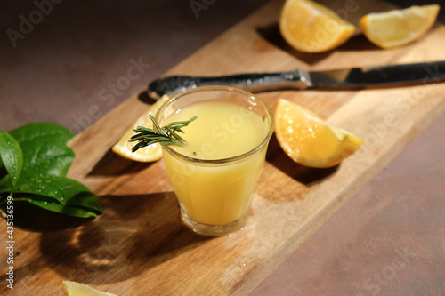 Alcoholic drink limoncello. Fresh lemons and shot glass of limoncello on table.