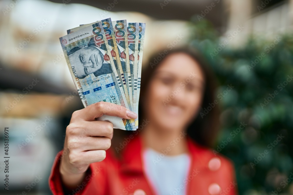 Young hispanic woman smiling happy holding peruvian sol banknotes at the city. - obrazy, fototapety, plakaty 