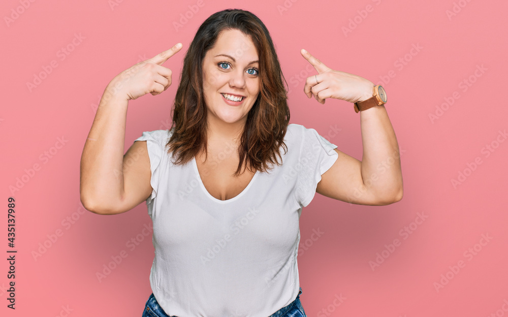Young plus size woman wearing casual white t shirt smiling pointing to head with both hands finger, great idea or thought, good memory Young plus size woman wearing casual white t shirt smiling pointing to head with both hands finger, great idea or thought, good memory