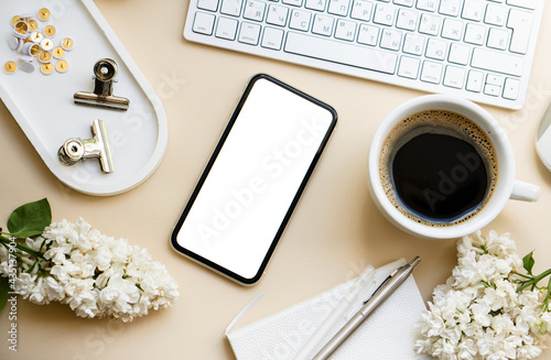 Neutral color tabletop with keyboard, lilac flowers and smartpohone mock-up with white screen isolated photo