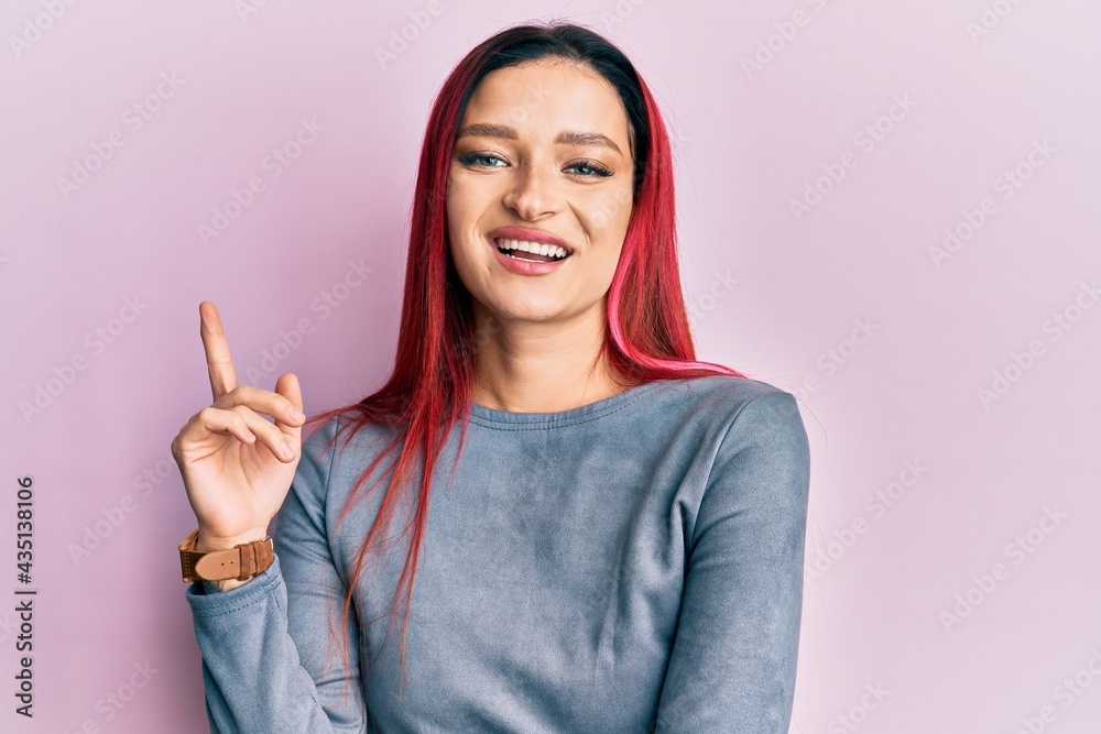 Young caucasian woman wearing casual clothes smiling with an idea or question pointing finger up with happy face, number one Young caucasian woman wearing casual clothes smiling with an idea or question pointing finger up with happy face, number one
