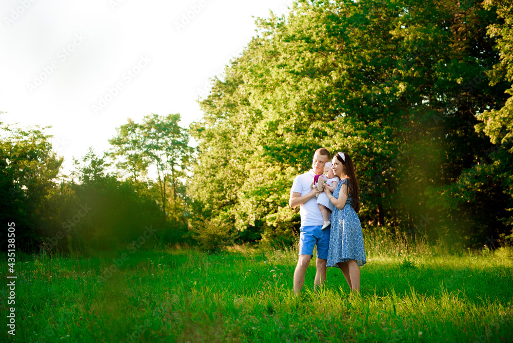 Fototapeta premium Happy family: mother father and child daughter in the park on sunset