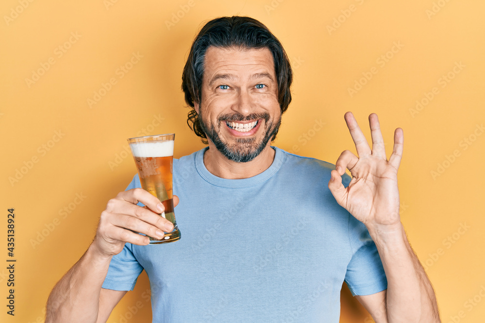 Middle age caucasian man drinking a pint of beer doing ok sign with fingers, smiling friendly gesturing excellent symbol Middle age caucasian man drinking a pint of beer doing ok sign with fingers, smiling friendly gesturing excellent symbol