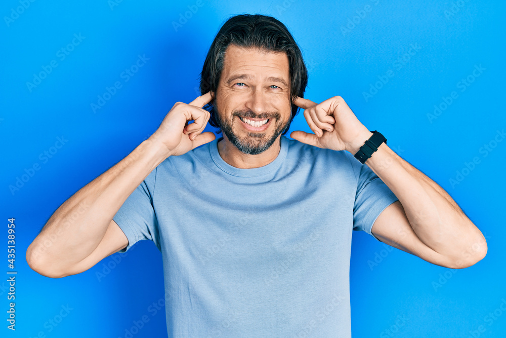 Middle age caucasian man wearing casual clothes covering ears with fingers with annoyed expression for the noise of loud music. deaf concept. Middle age caucasian man wearing casual clothes covering ears with fingers with annoyed expression for the noise of loud music. deaf concept.