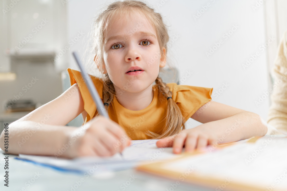 A tired little schoolgirl does her homework. A tired little schoolgirl does her homework.