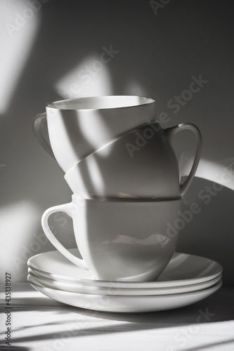 Three porcelain cups and saucers in the shade of a tree in black and white