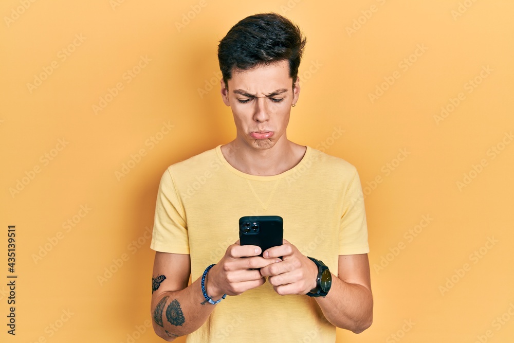 Young hispanic man using smartphone typing message depressed and worry for distress, crying angry and afraid. sad expression. Young hispanic man using smartphone typing message depressed and worry for distress, crying angry and afraid. sad expression.