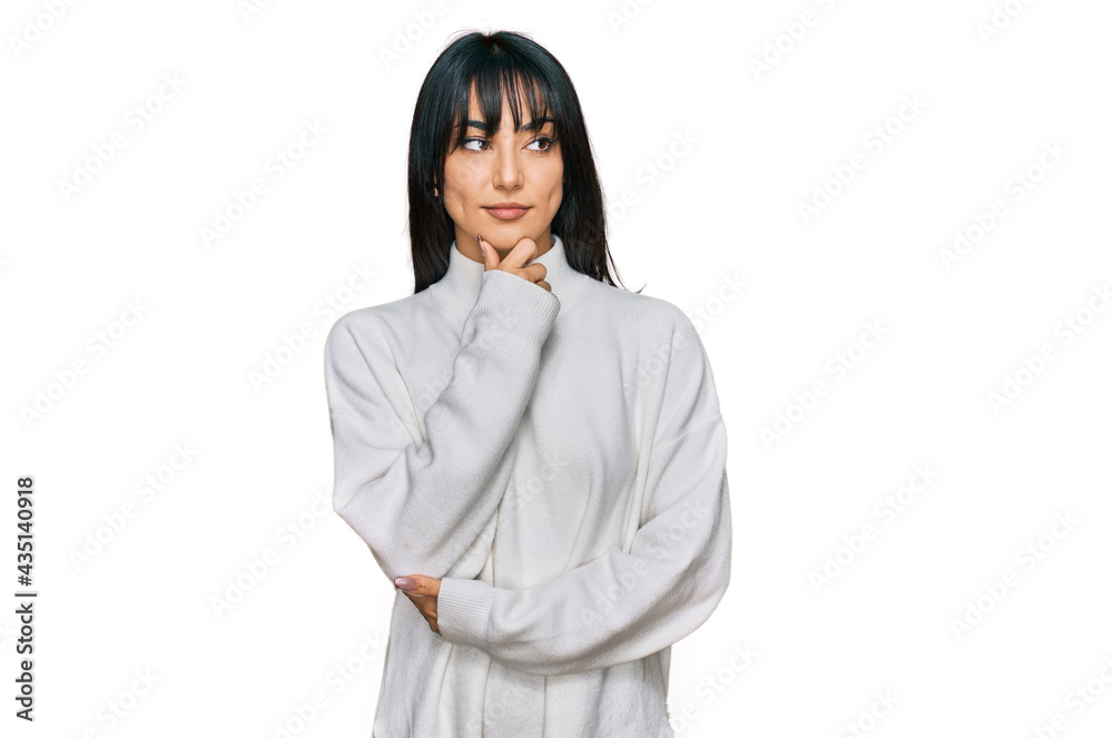 Young brunette woman with bangs wearing casual turtleneck sweater with hand on chin thinking about question, pensive expression. smiling with thoughtful face. doubt concept. Young brunette woman with bangs wearing casual turtleneck sweater with hand on chin thinking about question, pensive expression. smiling with thoughtful face. doubt concept.