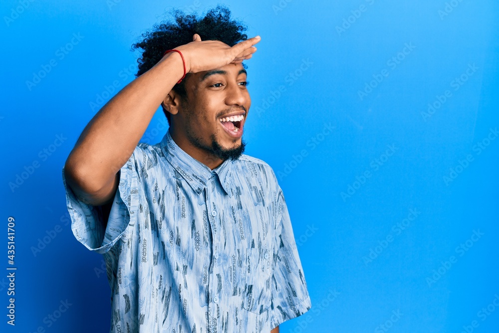© Krakenimages.com - Young african american man with beard wearing casual clothes very happy and smiling looking far away with hand over head. searching concept.