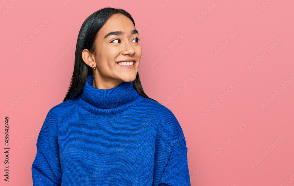 Young asian woman wearing casual winter sweater looking away to side with smile on face, natural expression. laughing confident. Young asian woman wearing casual winter sweater looking away to side with smile on face, natural expression. laughing confident.