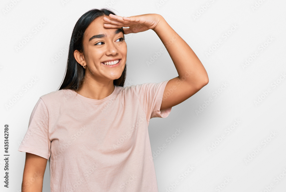 Young asian woman wearing casual clothes very happy and smiling looking far away with hand over head. searching concept. Young asian woman wearing casual clothes very happy and smiling looking far away with hand over head. searching concept.