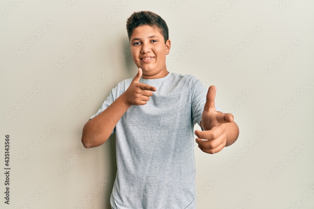 Teenager hispanic boy wearing casual grey t shirt pointing fingers to camera with happy and funny face. good energy and vibes. Teenager hispanic boy wearing casual grey t shirt pointing fingers to camera with happy and funny face. good energy and vibes.