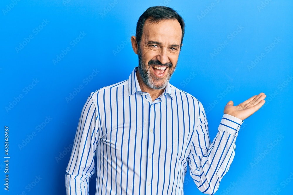Middle age hispanic man wearing casual clothes smiling cheerful presenting and pointing with palm of hand looking at the camera. Middle age hispanic man wearing casual clothes smiling cheerful presenting and pointing with palm of hand looking at the camera.