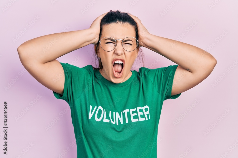 Young hispanic woman wearing volunteer t shirt crazy and scared with hands on head, afraid and surprised of shock with open mouth Young hispanic woman wearing volunteer t shirt crazy and scared with hands on head, afraid and surprised of shock with open mouth