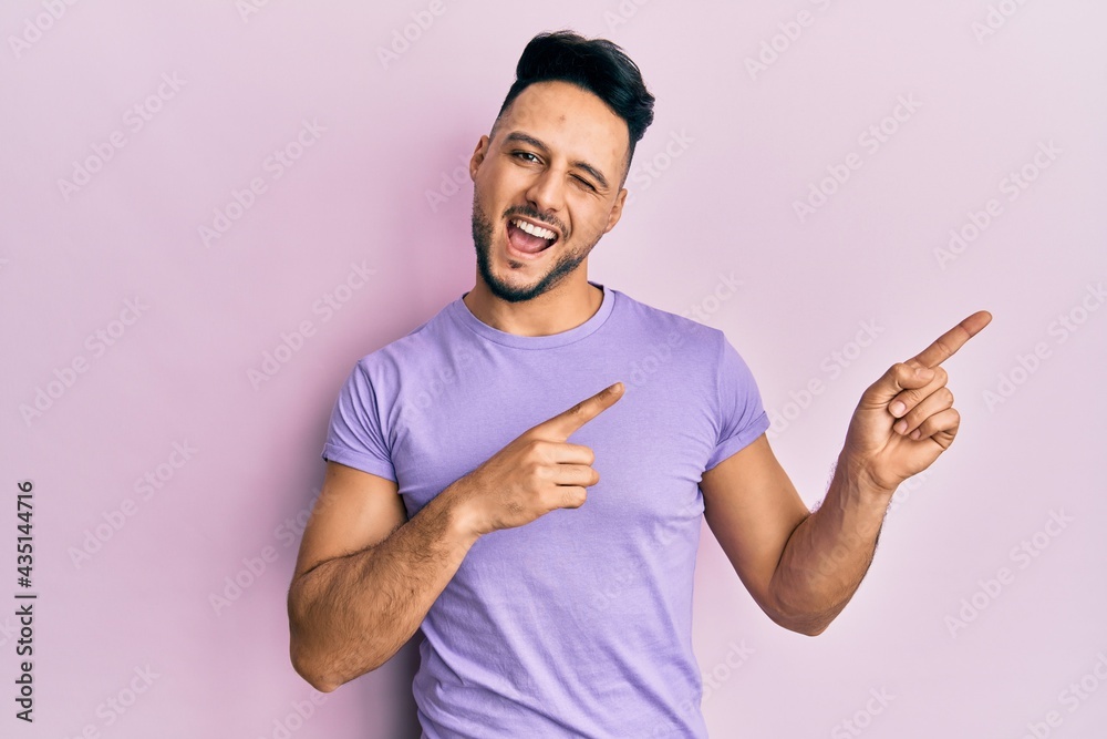 Young arab man wearing casual clothes smiling and looking at the camera pointing with two hands and fingers to the side. Young arab man wearing casual clothes smiling and looking at the camera pointing with two hands and fingers to the side.
