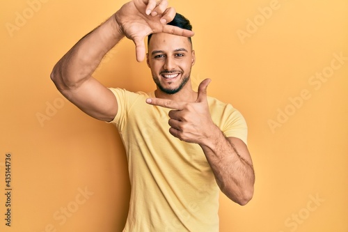 Young arab man wearing casual clothes smiling making frame with hands and fingers with happy face. creativity and photography concept.