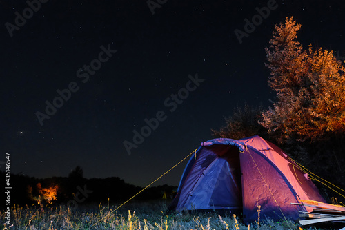 Tourist camping tent at night under starry sky. Country trip.