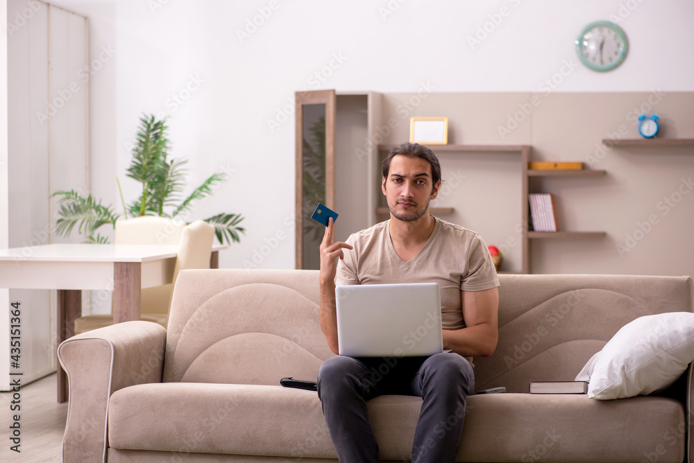 Young man ordering goods by credit card at home Young man ordering goods by credit card at home