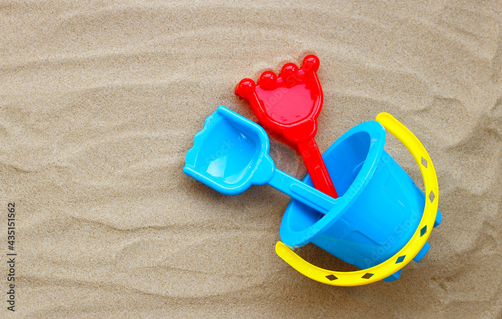 Plastic toys, shovel and bucket on sand on white background. Summer background concept Plastic toys, shovel and bucket on sand on white background. Summer background concept