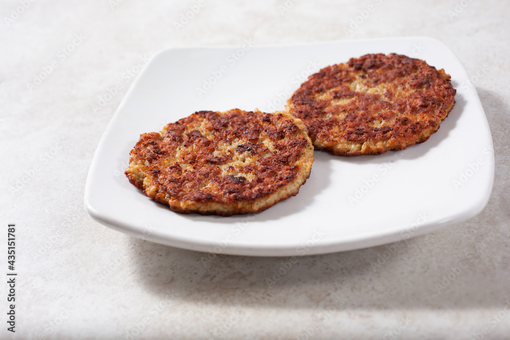 A view of two sausage patties on a plate.