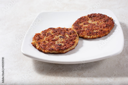 A view of two sausage patties on a plate.