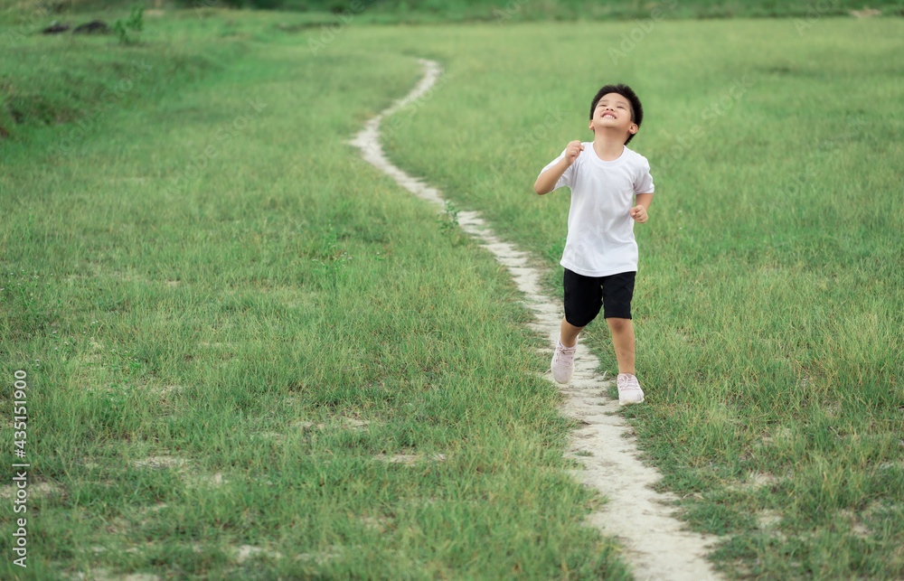 happy little Asian boy run on the field happy little Asian boy run on the field