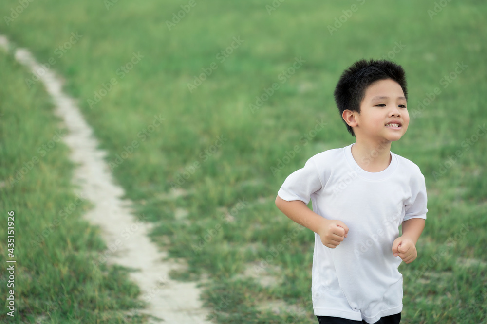 happy little Asian boy run on the field happy little Asian boy run on the field