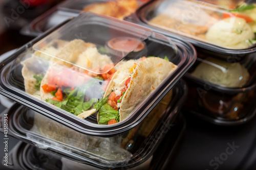 Fotografie, Tablou A view of several entrees prepared inside to-go plastic containers, ready for take out orders, in a restaurant setting