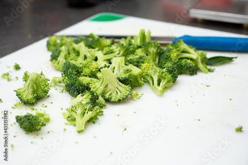 A closeup view of broccoli florets on a cutting board.
