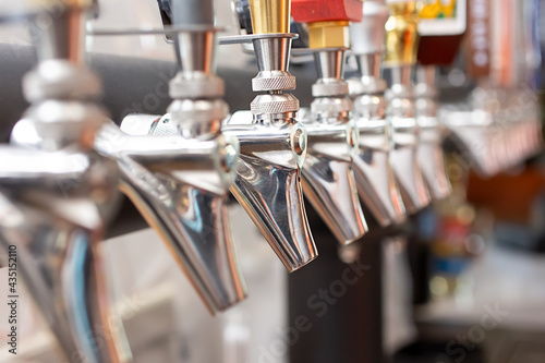A closeup view of several spout portion of beer taps, in a restaurant, bar or brewery setting. photo