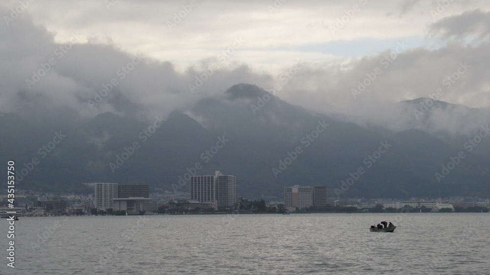 Cloudy mountain and a boat floating on Lake Biwa