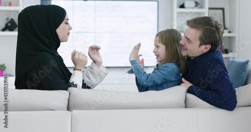 muslim famliy at home playing games on sofa with their kid photo