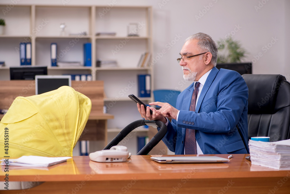 Aged businessman employee looking after newborn at workplace Aged businessman employee looking after newborn at workplace