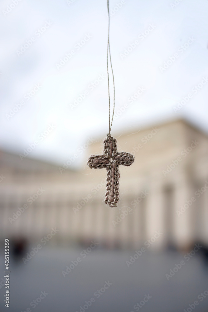 A knitted cross hangs in the sky before historic buildings in Vatican City. A knitted cross hangs in the sky before historic buildings in Vatican City.