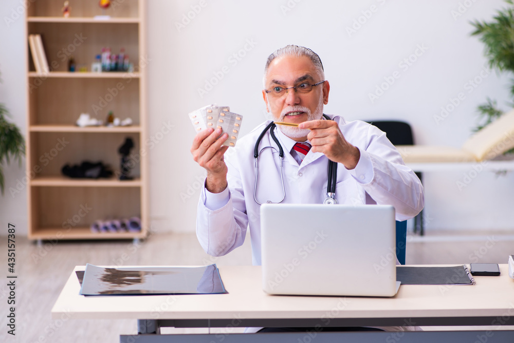Old male doctor holding pills