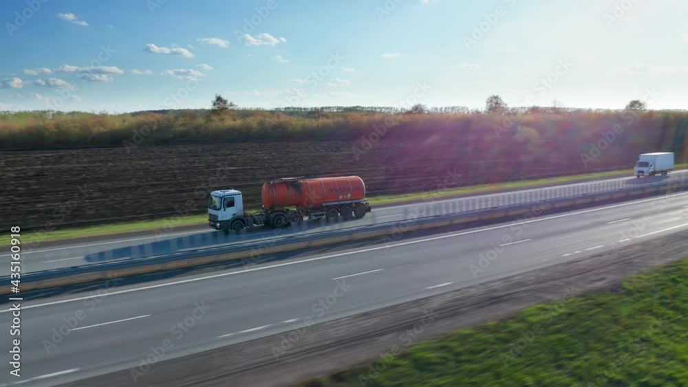 The tanker passes through the countryside. The semi truck with an orange-colored tank carries liquid fuel. Transportation of gasoline and diesel fuel. Oil company. High quality. 4k footage. The tanker passes through the countryside. The semi truck with an orange-colored tank carries liquid fuel. Transportation of gasoline and diesel fuel. Oil company. High quality. 4k footage.