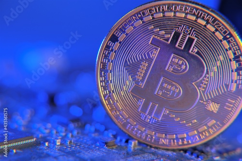 Bitcoin on electronic computer processor board in blue light.  Blockchain cryptocurrency.Cryptocurrency symbol. Bitcoin coin on  on computer motherboard, cryptocurrency investing 