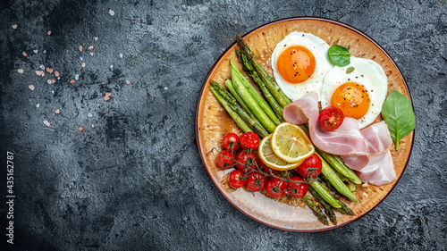 Plate with a keto diet food. Sunny side up eggs with green asparagus, bacon, ham and and cherry tomatoes. Keto breakfast. banner, menu recipe place for text, top view