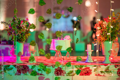 Fototapeta Naklejka Na Ścianę i Meble -  Birthday cake on the head table surrounded by colorful lighting and decorative arrangements. 50