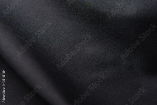 Closeup of rippled black silk fabric, black fabric texture background,