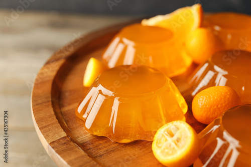 Plate with tasty orange jelly on wooden background, closeup photo