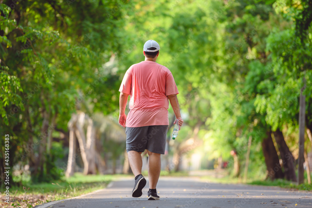Fat man exercising By walking to burn fat And run slowly to exercise in the park Fat man exercising By walking to burn fat And run slowly to exercise in the park