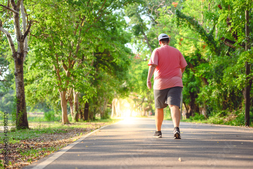 Fat man exercising By walking to burn fat And run slowly to exercise in the park