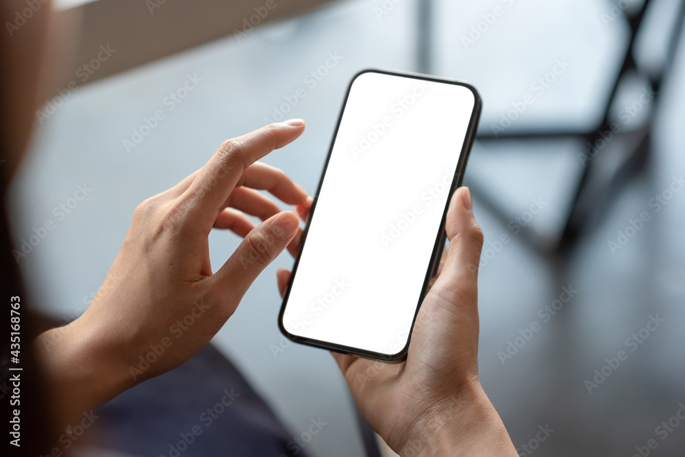 Close-up of a businessman hand holding a smartphone white screen is blank the background is blurred.Mockup. - obrazy, fototapety, plakaty 