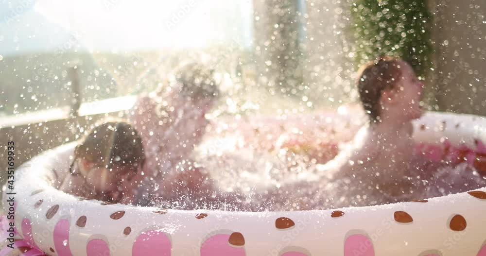 excited kids having fun, splashing water in inflatable pool at home patio, sunny summer activities