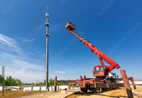 An aerial work platform, also known as an aerial device, elevating work platform, cherry picker, bucket truck, mobile elevating work platform maintenances the telecommunication tower. photo