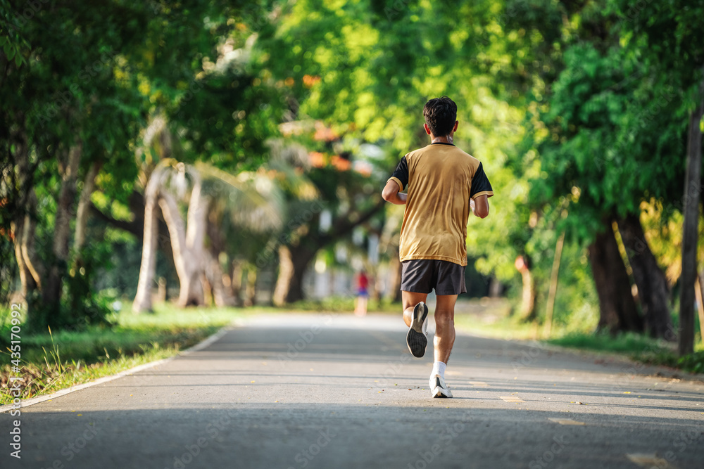 Back view of young man jogging or running exercising outdoors in park, Concept of healthy lifestyle. Back view of young man jogging or running exercising outdoors in park, Concept of healthy lifestyle.