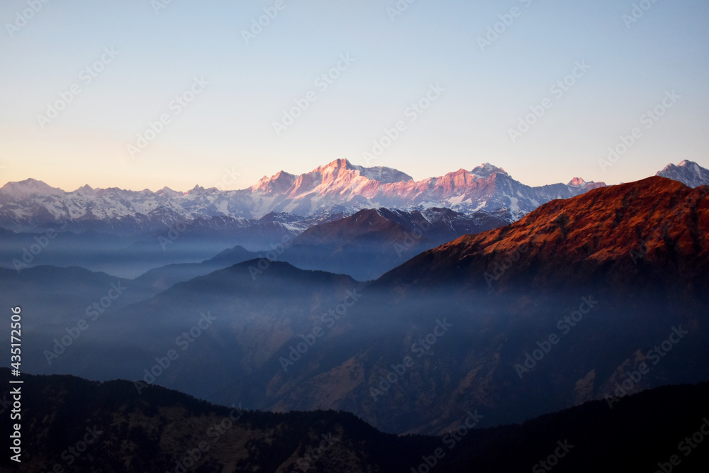 Beautiful landscape with high mountains with illuminated peaks, mountain,fog,snow,orange sky. Amazing scene with Tungnath  mountains. Uttarakhand,India.