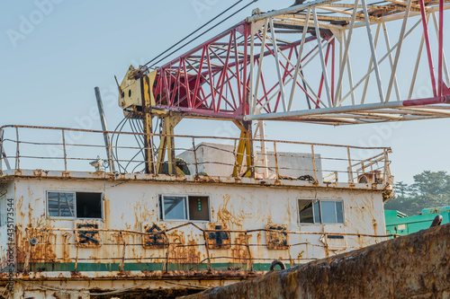 Fotografie Crane boom attached to upper deck of old rusty abandoned barge.