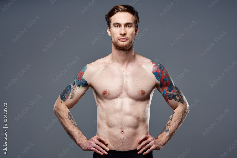 Fototapeta premium sporty man tattoos on his arms naked torso bodybuilder gray background